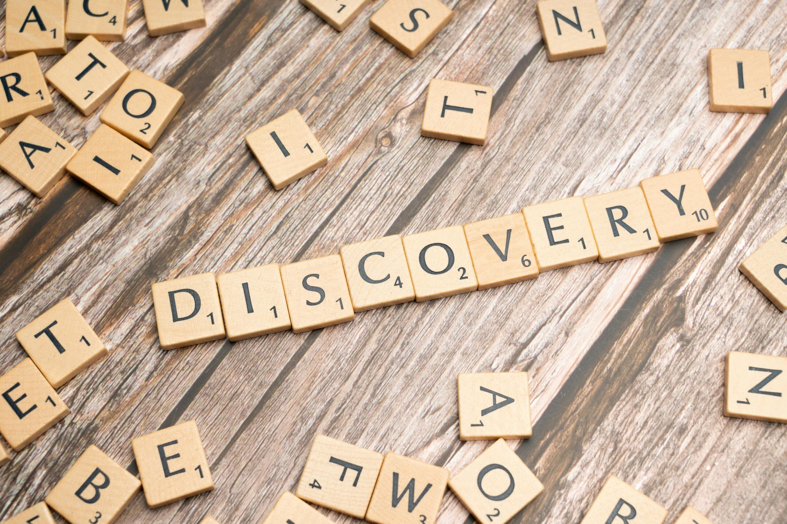 Close-up of wooden letter tiles on a table spelling 'Discovery', representing exploration and creativity.