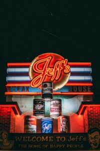 Vibrant neon sign at Jeff's Steakhouse in Warsaw, illuminating the night sky.